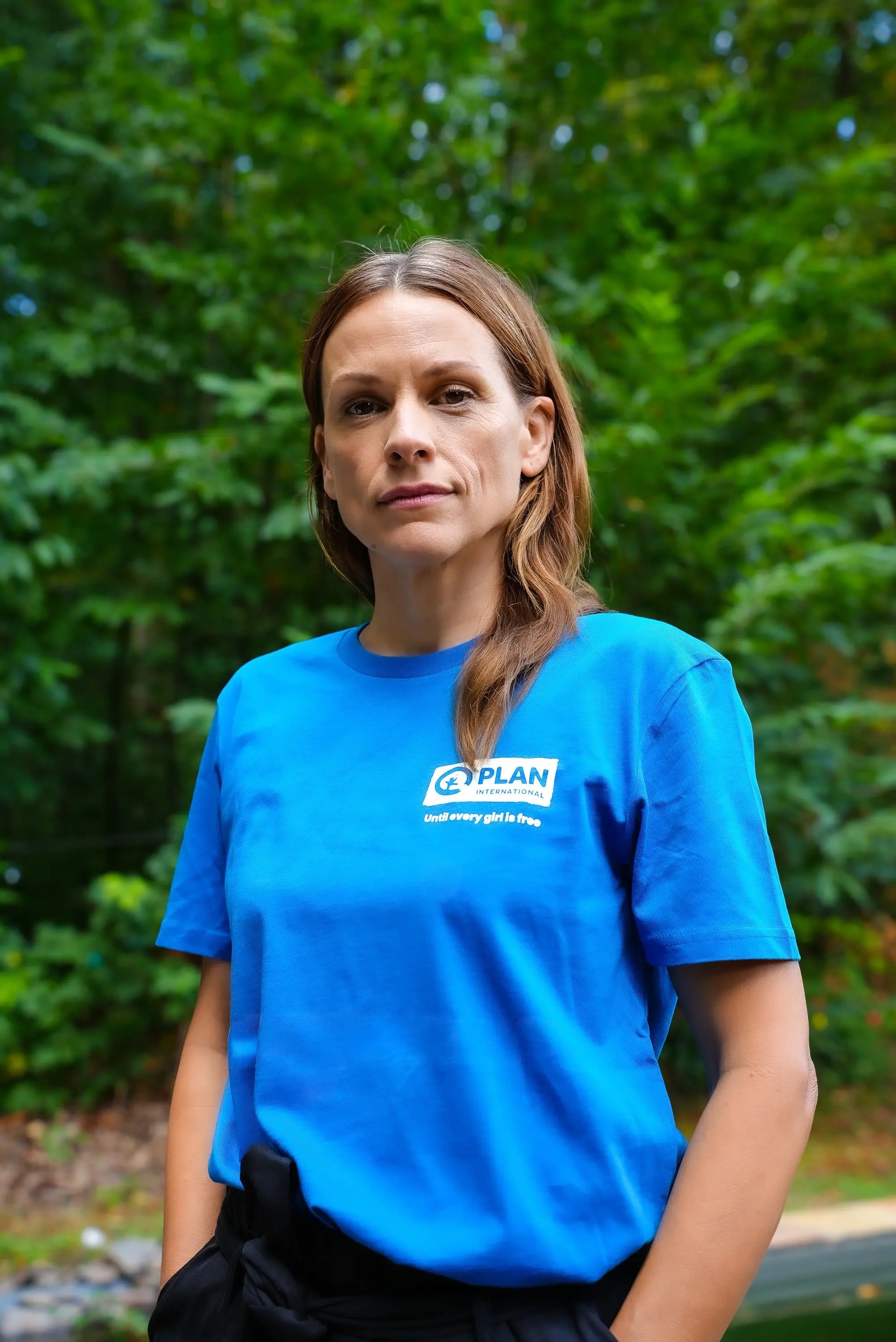 Veerle Baetens poseert buiten met een blauw T-shirt van Plan International België
